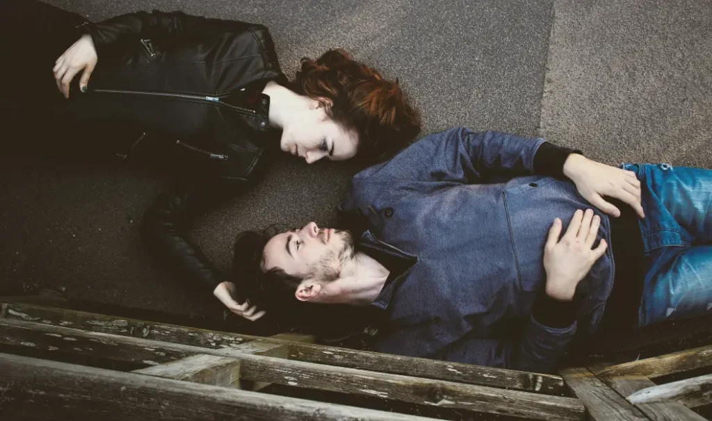 A couple lying on the ground, gazing into each other’s eyes with affection. A visual representation of love and connection, illustrating the meaning of 'Mi Corazón' as an expression of deep affection in Spanish.