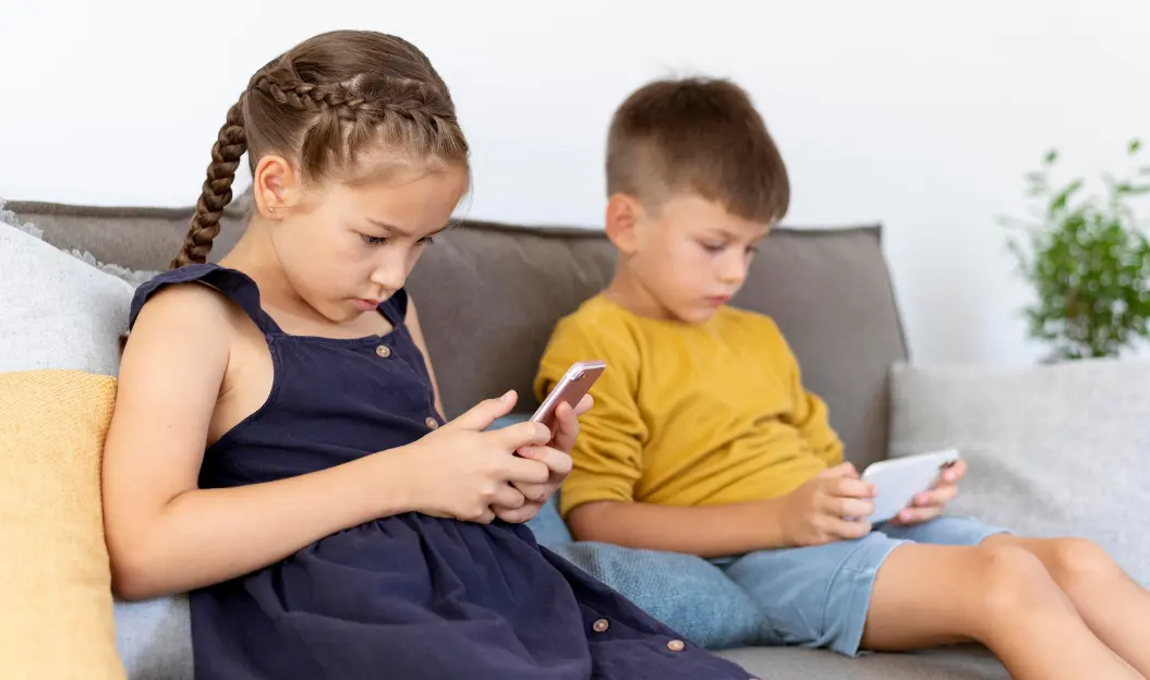 A Girl and Boy on a Couch Using Smartphones, Highlighting the Need for Balanced Screen Time Limits for Kids.